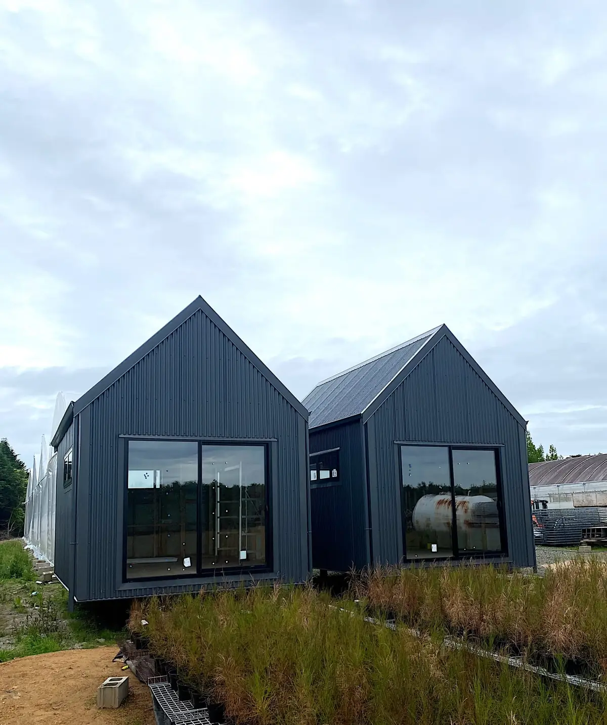 Two black corrugated steel gabled cabins with large sliding glass doors