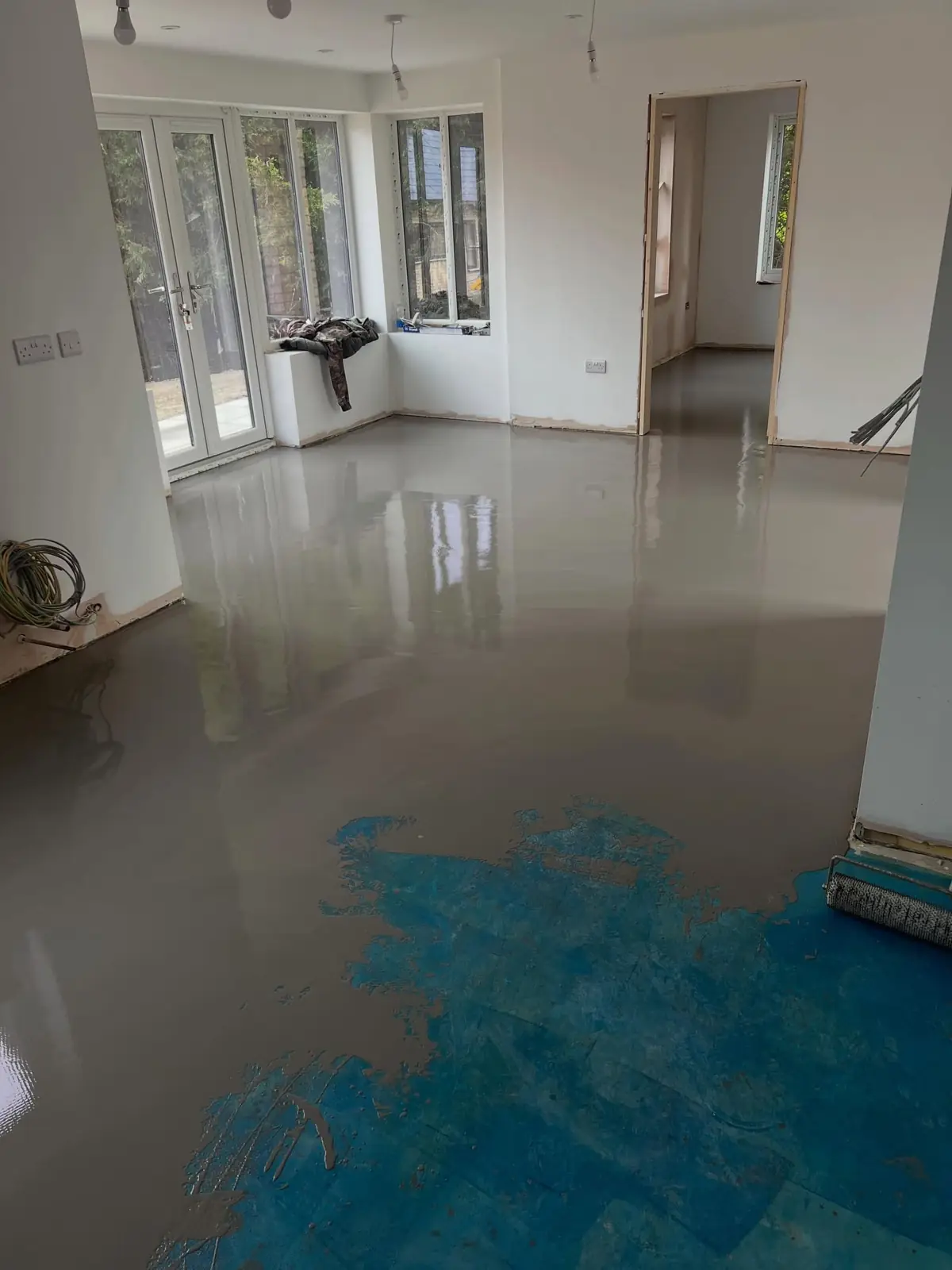 Self-levelling screed poured across an empty room ahead of a new floor